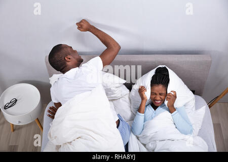 An Overhead View Of Couple Lying On Bed Disturbed By Noise Stock Photo
