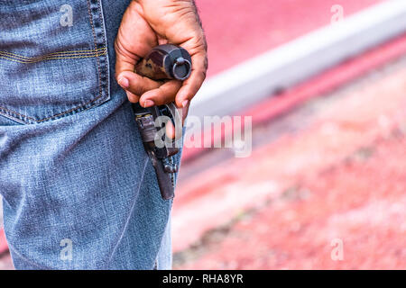 Starting Pistol in right hand of black male Starter at Athletic event. Finger on trigger. Stock Photo