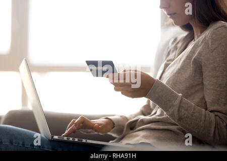 Female customer holding credit card paying online on laptop Stock Photo