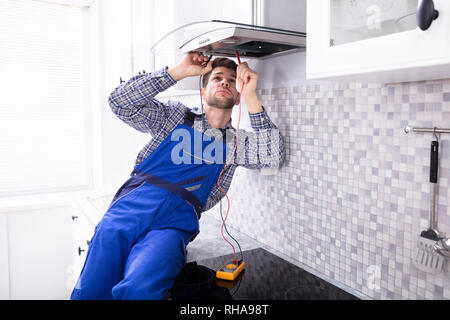 Handyman Checking Kitchen Extractor Filter With Multimeter In Kitchen Stock Photo