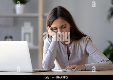 Bored funny woman resting on hand sleeping at workplace Stock Photo
