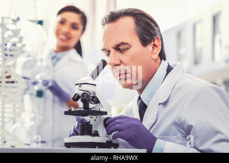 Old chemist wearing gloves working in laboratory Stock Photo