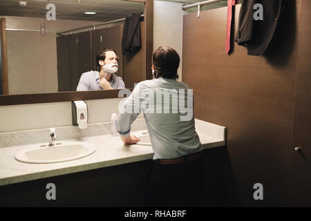 Business Man Shaving In Office Bathroom After Early Morning Commute Stock Photo