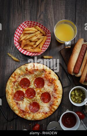 Party game day food Homemade Pizza hot dogs fries juice and dips - Super bowl food concept overhead view Stock Photo