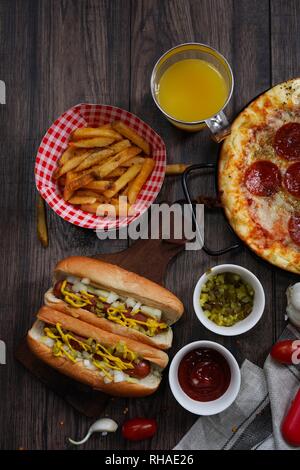 Party game day food Homemade Pizza hot dogs fries juice and dips - Super bowl food concept overhead view