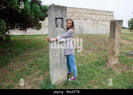 Young tourist girl embracing ancient stone sculpture Stock Photo