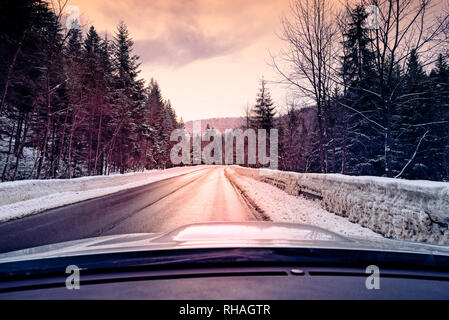 scenic view of empty road with snow covered landscape while snowing in winter season - view from the car Stock Photo