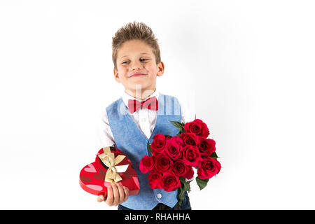 gentleman boy with blue vest, red butterfly tie,  red roses bucket and heart shaped gift box. Valentines day kids. Love and friendship. Woman Day Stock Photo