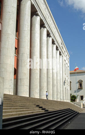 A customer entering the Central Post Office in Palermo, Sicily is dwarfed by the huge imposing columns and staircase of the massive building.  Built i Stock Photo