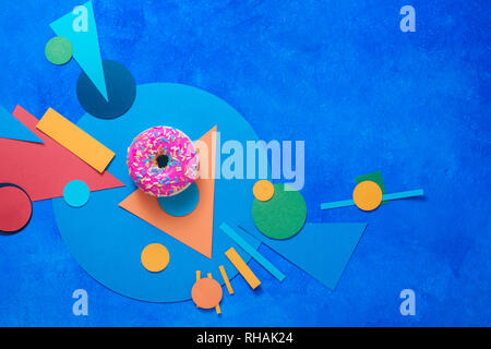 Pink glazed donut on a colorful background with geometric shapes. Color block food flat lay with copy space. Stock Photo