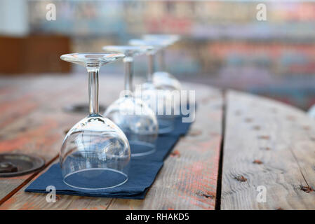 Empty wine glasses on rustic wooden table in retro restaurant interior. Stock Photo