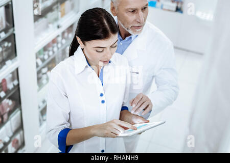 Two pharmacists in white coats working together in a drugstore Stock Photo