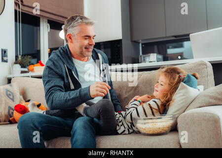 Adorable small long-haired girl and her father feeling wonderful at home Stock Photo
