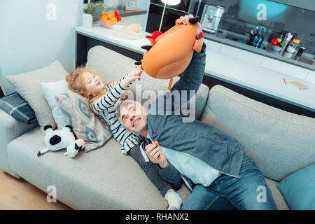 Cute long-haired girl in a dress and her father having fun Stock Photo