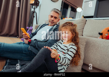 Tall handsome grey-haired father in sportswear looking interested Stock Photo