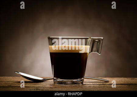 Black coffee in glass cup with teaspoon on wooden table Stock Photo
