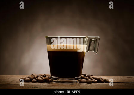 Black coffee in glass cup with coffee beans on wooden table Stock Photo