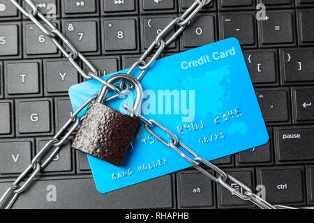 Credit card in chain with lock on laptop keyboard. Ban online payments and purchases in the online store. Stock Photo