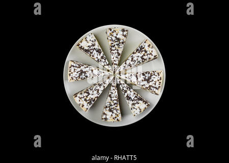 Cheesecake with chocolate chips on a white dish, isolated on the black background. Top view. Stock Photo