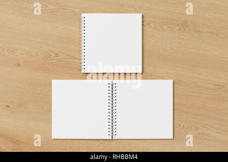 Blank open and closed square spiral notepad on wooden background. With clipping path around notebooks pages Stock Photo