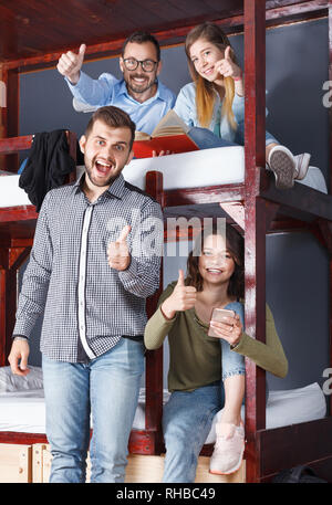 Portrait of positive glad travelers communicating while resting in modern cozy hostel bedroom Stock Photo