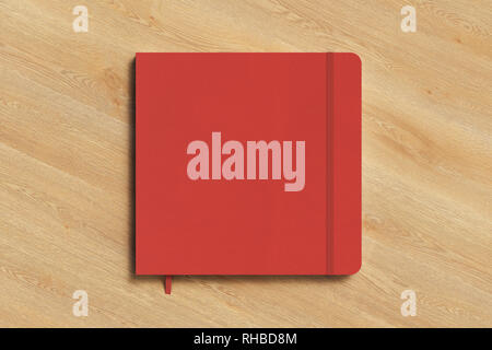 Red square notebook with elastic band on wooden background Stock Photo