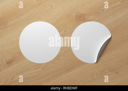 Blank white round stickers straightened and with folded corner on wooden background. With clipping path around stickers. Stock Photo