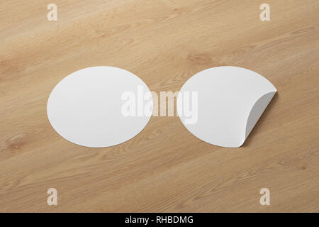 Blank white round stickers straightened and with folded corner on wooden background. With clipping path around stickers. Stock Photo