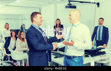Two successful businessmen shaking hands in office confirming partnership Stock Photo