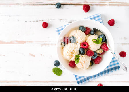 Top view of vanilla ice cream with berries in a bowl on white wooden table Stock Photo