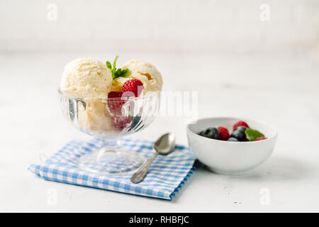 Vanilla ice cream in a glass cup with berries on white background