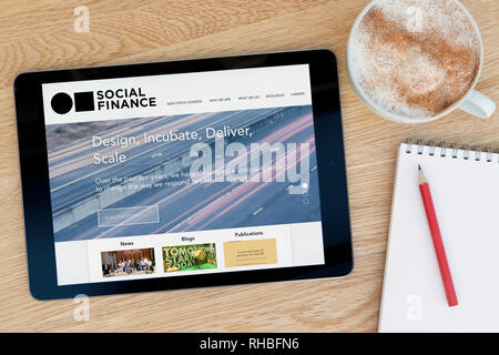 The Social Finance website features on an iPad tablet device which rests on a wooden table beside a notepad (Editorial use only).