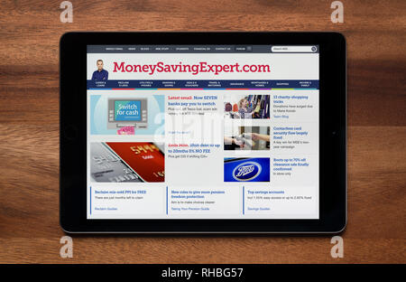 The website of MoneySavingExpert is seen on an iPad tablet, which is resting on a wooden table (Editorial use only). Stock Photo