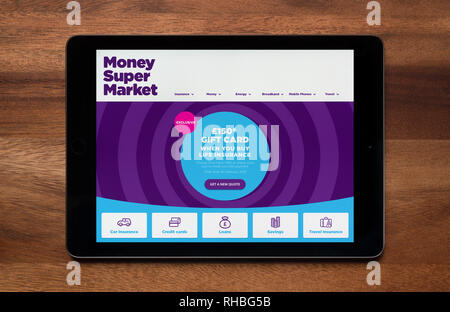 The website of MoneySuperMarket is seen on an iPad tablet, which is resting on a wooden table (Editorial use only). Stock Photo