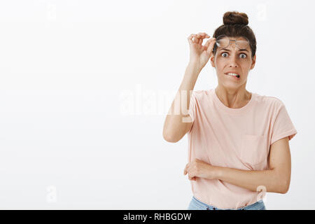 Waist-up shot of scared worried and insecure young silly woman taking off glasses biting lower lip and frowning, feeling intense and nervous as Stock Photo