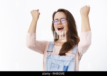 Yeah baby we did it. Portrait of relieved and thankful happy woman celebrating victory, triumphing yelling yes with hands raised in sky and closed Stock Photo
