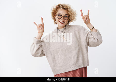 Free Photo  Attractive young girl with short hair, wearing glasses and  street style clothes, leaning on a brick wall.