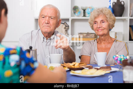 Stressed senior couple having conversation with female over cup of coffee at home Stock Photo