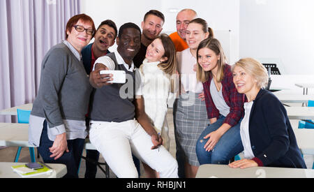 Multinational group of of happy adult students taking selfie in auditorium Stock Photo