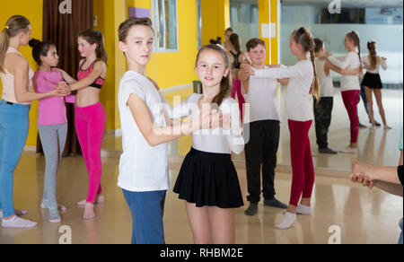 Group of tweens training movements of slow foxtrot in dance studio with female coach Stock Photo
