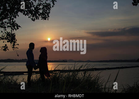 Silhouette photo of two lovers with sunset background Stock Photo