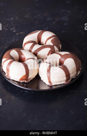 Striped donuts on dark wooden table. Delicious snack. Stock Photo