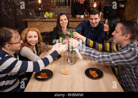 Happy young friends group making a toast about their friendship. Hipster pub. Stock Photo