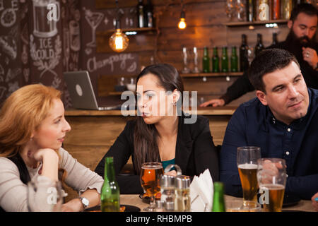 Friends in the pub drinking beer talking and having fun. Hipster pub. Stock Photo
