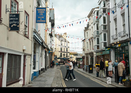 View along the busy and popular, historic Southside Street, Barbican, Plymouth with people enjoying colourful shops and pubs, with bunting overhead. Stock Photo