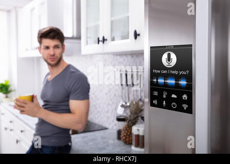 Man Standing Near Oven With Voice Recognition Function In Kitchen Stock Photo