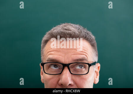 Close-up Of Mature Man Looking Up Against green Background Stock Photo