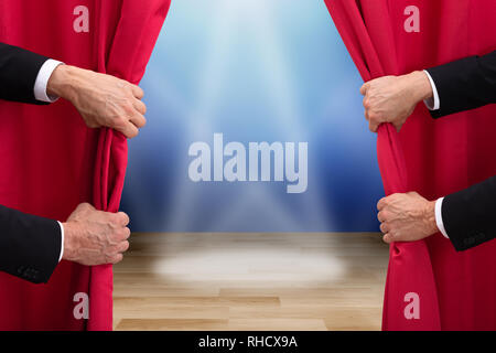 Two People Opening Red Curtain With Spots Lights On Stage Stock Photo