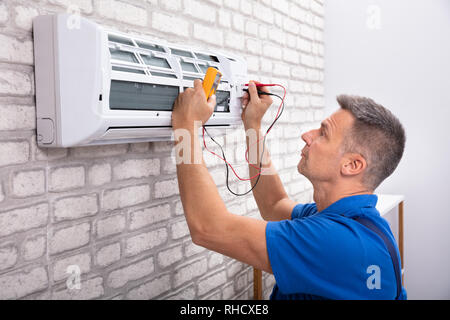 Male Electrician Checking Air Conditioner With Digital Multimeter Stock Photo