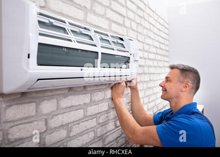 Mature Male Technician Fixing Air Conditioner With Screwdriver Stock Photo